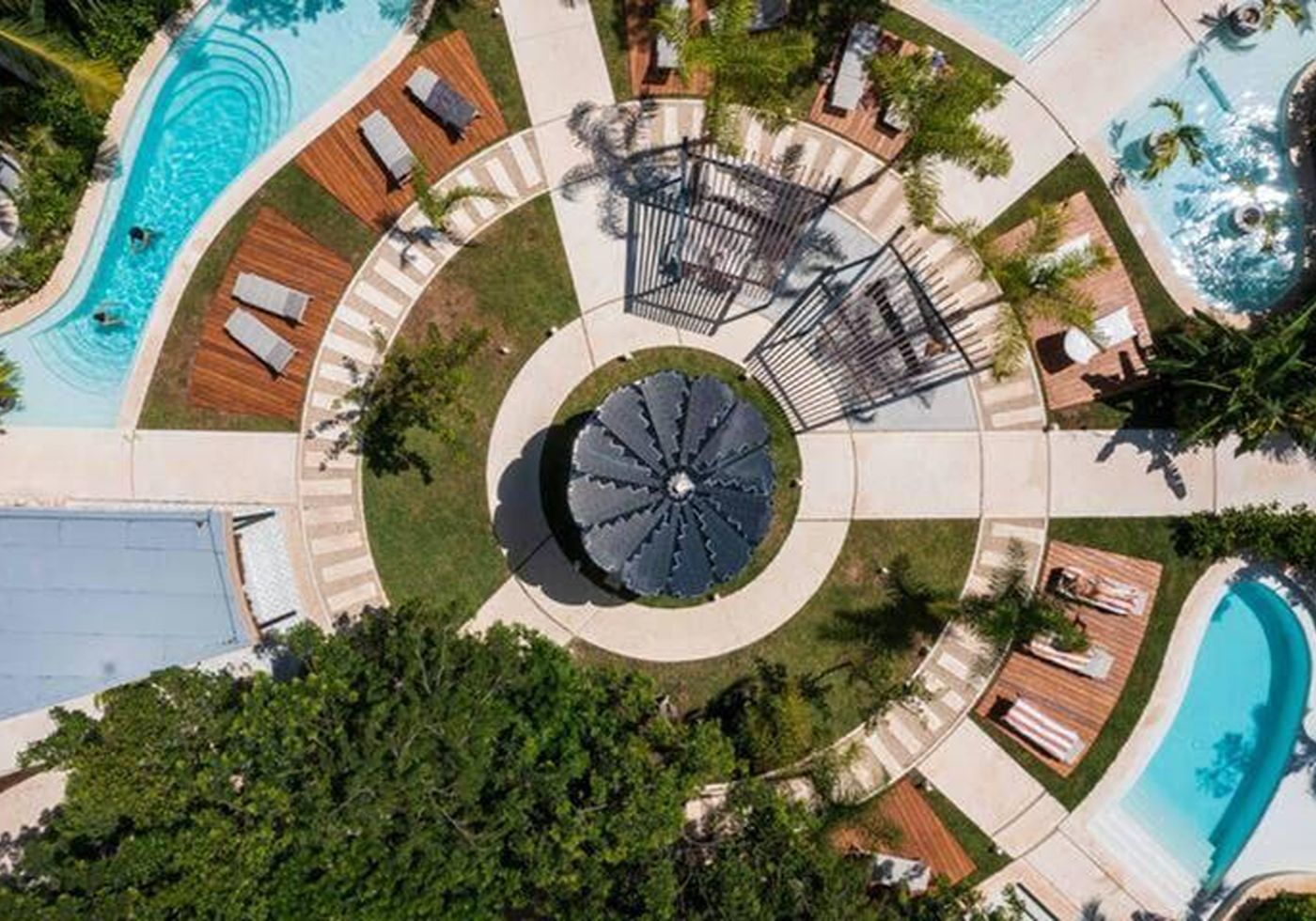 Aerial view looking down through trees onto one of the development’s pools