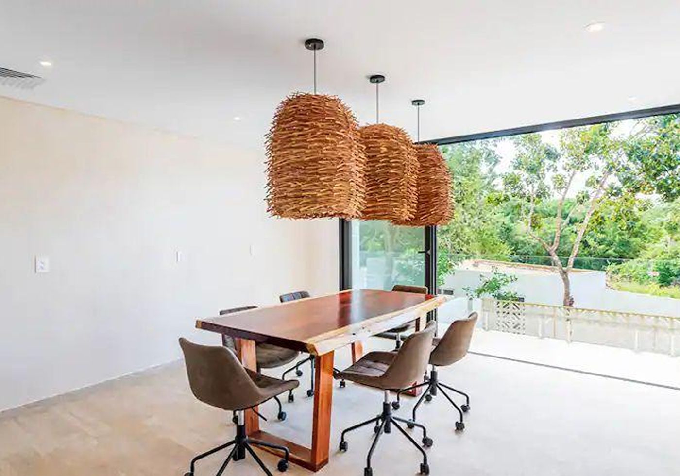 Shared coworking and dining lounge at Central Park Lagunas, with rattan pendant lighting