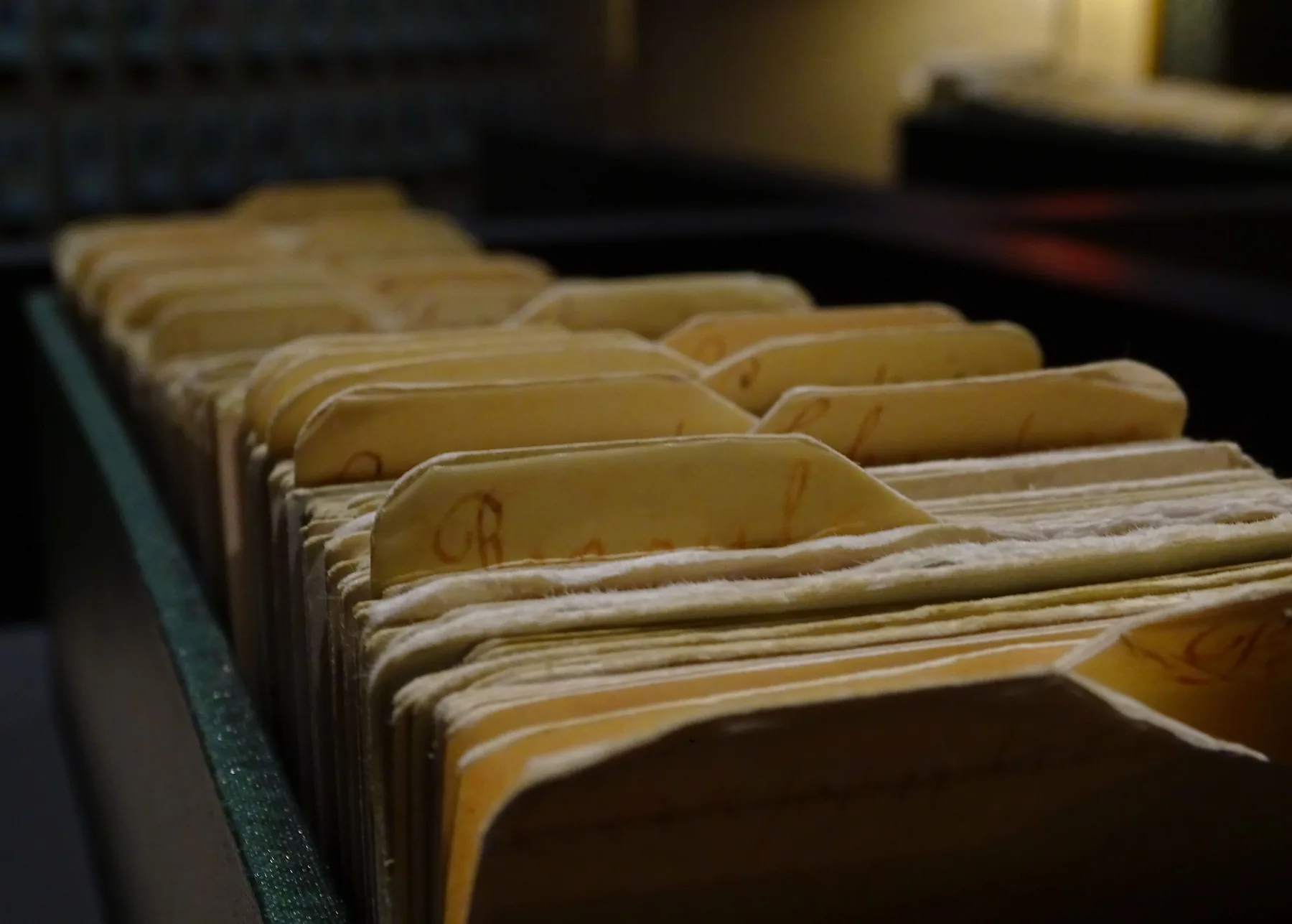 Rows of worn file folders standing upright inside an archive drawer