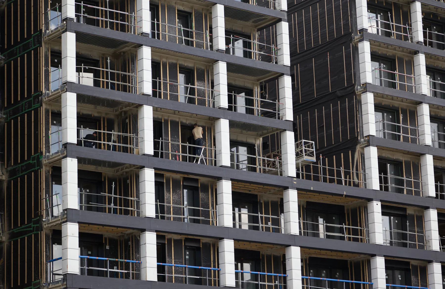 High-rise building under construction, concrete floors framed and scaffolding running up the facade